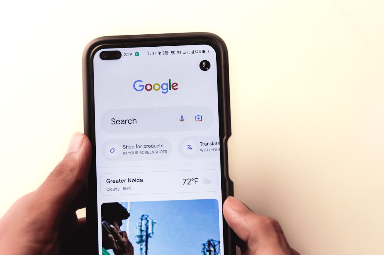 Services-02 A close-up of a hand holding a smartphone with Google search displayed on the screen.